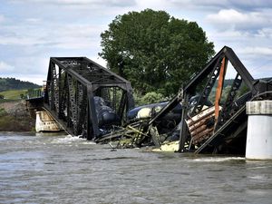 Several train cars are immersed in the Yellowstone River after a bridge collapse near Columbus, Mont., on Saturday, June 24, 2023.   The bridge collapsed overnight, causing a train that was traveling over it to plunge into the water below. (AP Photo/Matthew Brown)